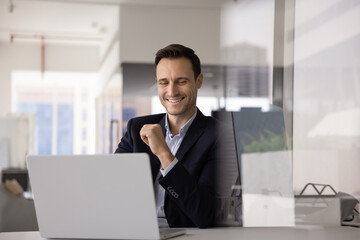 Happy business executive man working at computer at office workplace, typing, laughing, using job application, software, web service for online communication. Candid shot with copy space