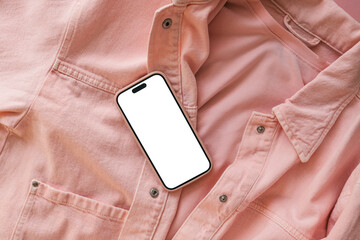 Modern smartphone with blank white screen on pink denim jacket and t-shirt. Mobile phone with empty display mockup. Fashion and technology concept. Front view, flat lay