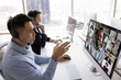 © fizkes - Asian telemarketing agency employee man talking to diverse group of coworkers on video conference chat, using headset and monitor for communication, attending online training