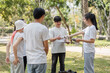 © wichayada - Community engagement. Group of volunteers discussing cleanup plans in the park.
