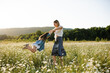 © morrowlight - Mother playing with child girl 4-5 year old in blooming chamomile meadow wearing casual dresses outdoors. Springtime. Motherhood.