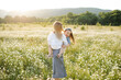 © morrowlight - Mother playing with child girl 4-5 year old in blooming chamomile meadow wearing casual dresses outdoors. Springtime. Motherhood.