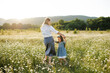 © morrowlight - Mother playing with child girl 4-5 year old in blooming chamomile meadow wearing casual dresses outdoors. Springtime. Motherhood.