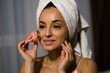© Nataliya - Close up of Caucasian young attractive woman with towel on head using microcurrent facial toning device at home. Beauty device. Beautiful happy female using skincare device