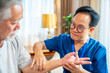 © CandyRetriever  - Asian senior man patient doing rehab physical therapy stretching muscle arm, hand and fingers with physiotherapist caregiver in bedroom. Home medical caregiving services and elderly people healthcare.