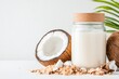© Olga - Fresh coconut milk in glass jar with coconut shells on white surface