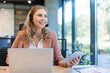 © ty - Customer support service. Close-up of caucasian friendly smiling woman, call center operator with headset, working on support hotline in a modern office with a laptop