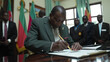 © tiagozr - Government official signing security bill with military officers observing.