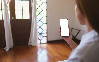 Wall Mural - mockup image of a woman holding mobile phone with blank desktop screen at home
