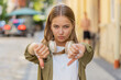 © Andrii Iemelianenko - Dislike. Upset Caucasian young woman showing thumb down sign gesture, expressing discontent disapproval, dissatisfied bad work mistake outdoors. Displeased girl female on urban city street. Horizontal
