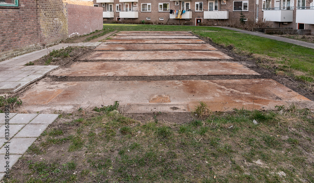 rusty steel terrain plates lie outside on a lawn in a residential area