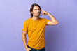 © luismolinero - Young handsome man isolated on purple background making the gesture of madness putting finger on the head
