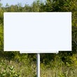 © Mongkol - Blank Billboard Standing in a Green Field Under Clear Blue Sky
