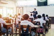 © EduLife Photos - Students in white uniforms attentively listen to their teacher in a well-lit classroom