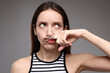 © New Africa - Funny woman holding finger with drawn mustache above lips on grey background