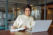 © Stock 4 You - Portrait young latina or indian business woman using laptop pc working at desk writing notes, watching educational online webinar. Female student looking at computer screen device, studying in office