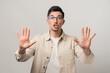 © Andrei - Stop. Calm down. A reassuring man in eyeglasses and a beige overshirt holding his hands up with open palms, gesturing for peace