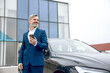 © zinkevych - Businessman using his smartphone while standing at dealership