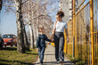 © Dusan Petkovic - Full length of a mother walking with her schoolboy on a city street.