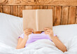 © Prostock-studio - Unrecognizable Girl Reading Book Lying In Bed At Home. Bookworm, Weekend Leisure Concept.