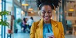 © LukaszDesign - Employee wearing headphones and on the phone, joyfully browsing social media and smiling as she receives good news on her mobile device in a corporate environment