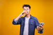 © Gatot - Portrait Of Young Asian Guy In Casual Style Texting On Smartphone And Drinking Coffee Cup While Standing Against Yellow Background