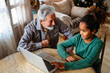 © NDABCREATIVITY - Mature couple with grandchild look at laptop screen and learn how to make video call or use laptop