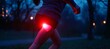 © Nathamanee - A woman running in the woods with a red light on her leg