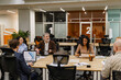© Drobot Dean - A group of five employees sit at a table and listen to a man sitting next to them holding a laptop, at work, during retirement