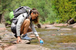 © Antonioguillem - Hiker woman filling canteen from river in the mountain