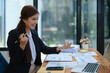© Jirapong - Confident business woman smiling Show successful gestures at her desk with market charts and documents in office
