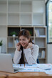 © Jirapong - Confident business woman smiling Show successful gestures at her desk with market charts and documents in office