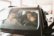 © Serhii - A joyful family sitting inside a new car at a dealership