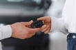 © Serhii - Young Caucasian woman buys a car at a dealership. Bearded man seller gives the car keys