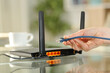 © PheelingsMedia - Woman hand holding ethernet cable ready to plug in modem