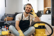 © standret - Enjoying music. Sitting. Male professional cleaning service worker is domestic room