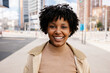 © Xavier Lorenzo - Happy young African American girl smiling at camera standing at city street. Outside portrait of joyful beautiful black woman over urban background