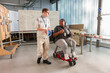 © Caia Image - Disabled man and woman talking in workshop