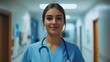 © Saif - A young female nurse standing in a hospital corridor, confidently holding a stethoscope. She is wearing scrubs and has a warm smile