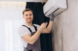 © anatoliycherkas - Technician installing and checking air conditioning with remote control