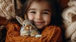 © Raul - Smiling young girl is holding a small brown and white rabbit in her arms while wrapped in a chunky knit orange sweater and surrounded by a textured cr