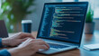 © Nano Photos - A person coding on a laptop, displaying lines of code; a typical scene of software development or programming work.