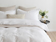 © Vera - Bedroom with a double bed, fluffy down comforter with a duvet cover, four pillows, one beige cushion and bedside table with vase. Close-up front view vertical photo. Suitable for mockup