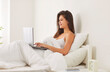 © Studio Romantic - Positive woman spends morning leisure time in bed, using a laptop for online entertainment at home. She enjoys the internet, finding relaxation and joy in comfortable home environment.