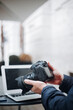 © jorge - Professional photographer examining digital images on camera screen, editing photos with laptop nearby at sleek workspace