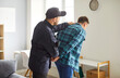 © Studio Romantic - Policeman arresting a man suspect or criminal, placing handcuffs on hands at home living room, emphasizing law enforcement role in custody and crime prevention. Police action under the law.