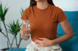 © zigres - Eating Disorder. Unrecognizable girl suffering from abdominal pain holds a glass of water in her hand. Unregulated Intestine.