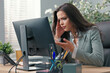 © ABCreative - Beautiful busy businesswoman sits at desk in front of computer in office, has technical problems with monitor, wrong screen setting, no signal, error, keyboard not working
