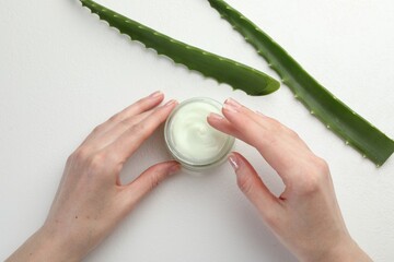 Wall Mural - woman with moisturizing cream and aloe vera leaves at white textured table, top view