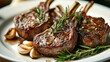 © hdesert - Grilled lamb chops with a seared crust are garnished with fresh rosemary and coarse salt, served alongside roasted garlic cloves on a white plate